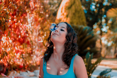 Close-up of young woman standing against trees in park