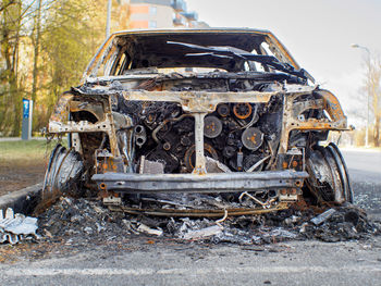 Close low angle front view to the burned car on the street during the day. 