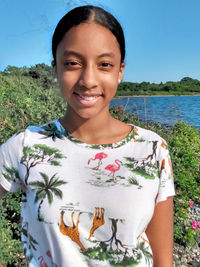 Portrait of smiling young woman standing against plants
