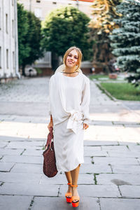 Portrait of smiling young woman walking on road in city