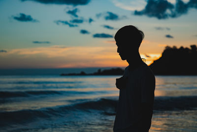 Silhouette man looking at sea against sunset sky