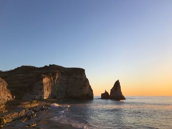 Rock formations in sea against clear sky