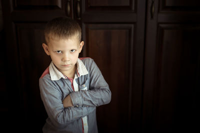Boy is serious and offended, the concept of children's emotions, brown background in real interior