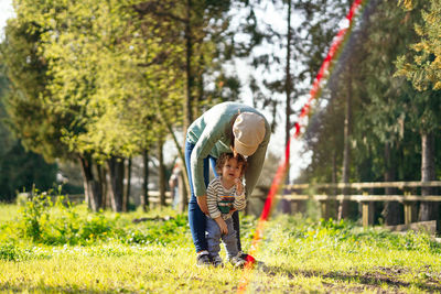 Rear view of boy and plants against trees