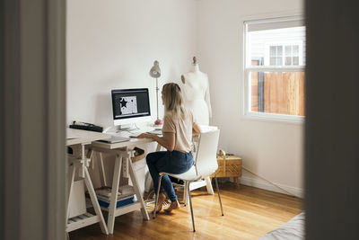 Rear view of woman sitting on chair at home