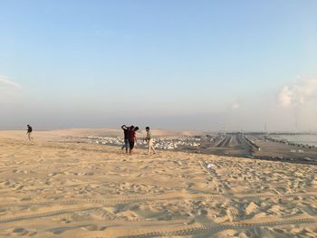 Rear view of people on beach against sky