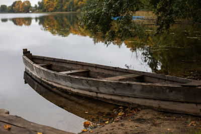 Old wooden fishing boat stands on the lake in the village of autumn in cloudy weather