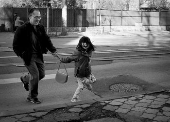 Girl with father walking on road in city