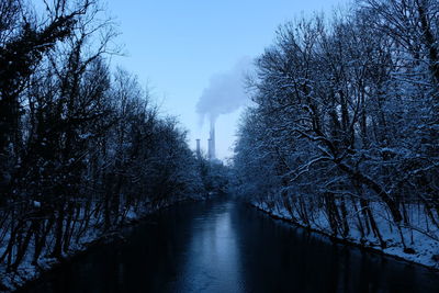 Canal amidst bare trees against sky during winter