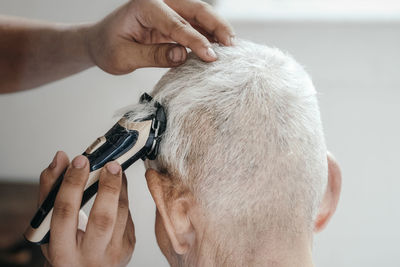 Cropped hands of grandson cutting senior man hair