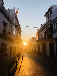 Street amidst buildings against sky during sunset