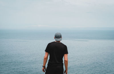 Rear view of man standing against sea
