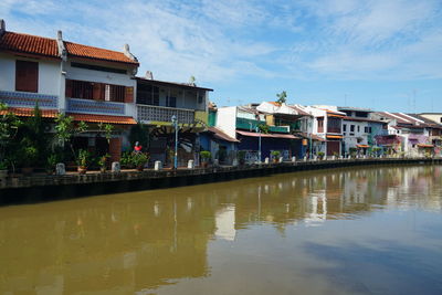 Canal by houses against sky in city