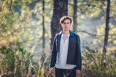 Portrait of young man standing in forest