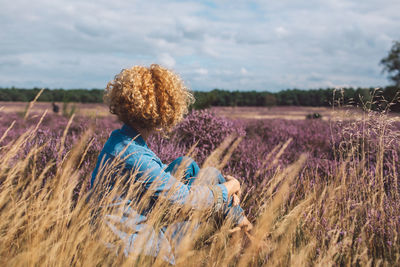 Rear view of woman standing on field against sky