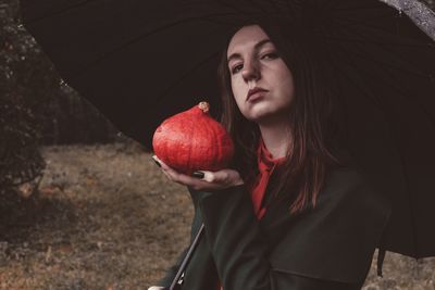 Close-up of woman holding strawberry while standing outdoors