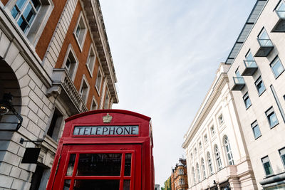 Traditional red telephone box in london, england, uk. low angle view against sky in covent garden 