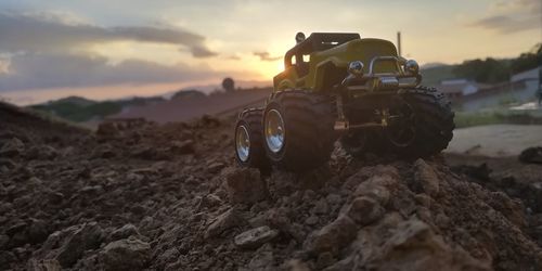 Tractor on field against sky during sunset