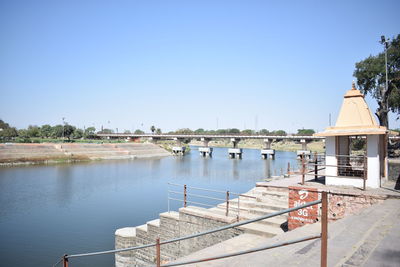 Scenic view of river by buildings against clear blue sky