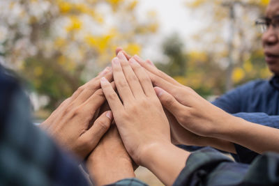 Cropped hand of people stacking hand outdoors