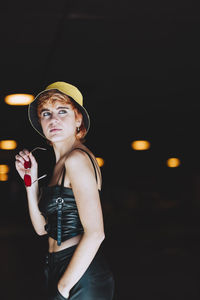 Thoughtful young woman holding sunglasses at underpass