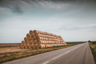 Road by agricultural field against sky