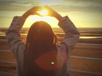 Woman holding hands at sunset