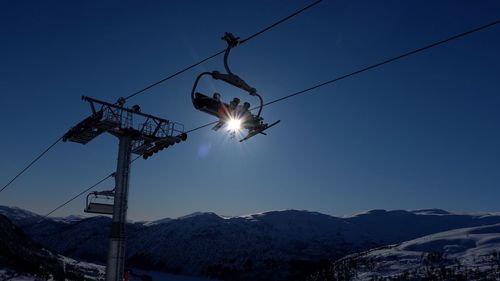 Low angle view of ski lifts over mountains against clear blue sky