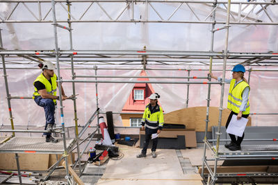 High angle view of coworkers listening to manager while standing in construction site