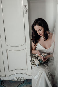 Bride holding bouquet sitting by door