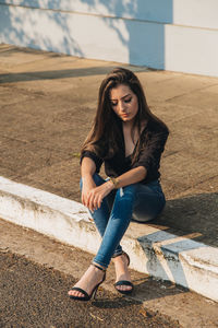 High angle view of young woman sitting on footpath
