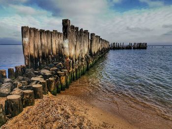 Wooden posts on beach against sky