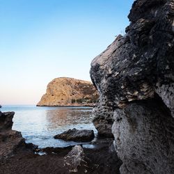 Rock formation in sea against clear sky