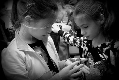 Sisters looking at snail on palm of hand