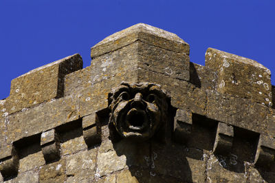Low angle view of sculpture on historic building against blue sky