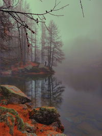 Scenic view of lake with person in the distance against sky during foggy weather 