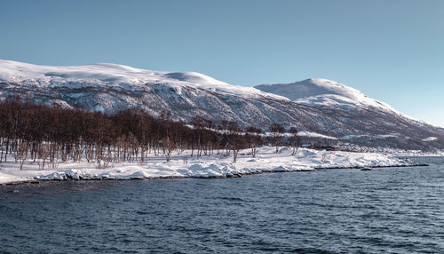 Scenic view of frozen sea by snowcapped mountain against sky