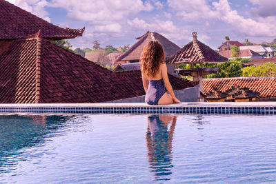 Woman by swimming pool against sky