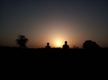 Silhouette people on field against sky during sunset