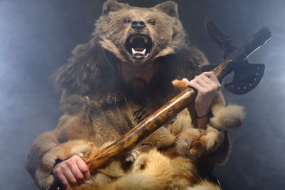 Portrait of a man bearded scandinavian shaman with axe on hands and a bear skin on his head