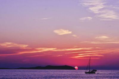 Boats sailing in sea at sunset