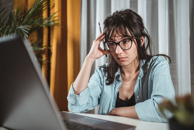 Young woman using mobile phone while sitting on table