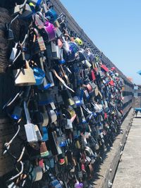 Padlocks hanging on fence against sky