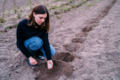 Portrait of young woman sitting on sand at beach