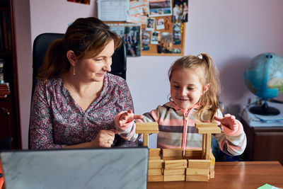 Smiling girl playing with block shape with mother at home