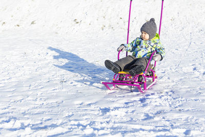 A small child sledding in the winter on white snow, outdoors.