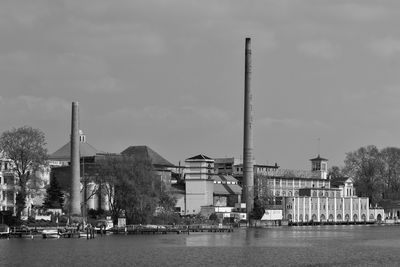 Buildings by river against sky in city