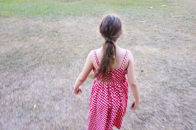 Rear view of girl walking on field