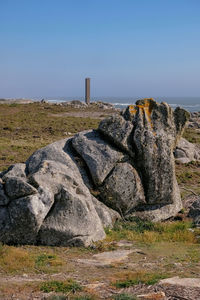 Rock formations on shore against clear sky