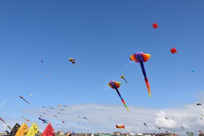 Low angle view of kites flying against clear blue sky